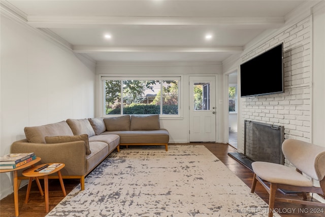 living room with a brick fireplace, dark hardwood / wood-style flooring, ornamental molding, and beam ceiling