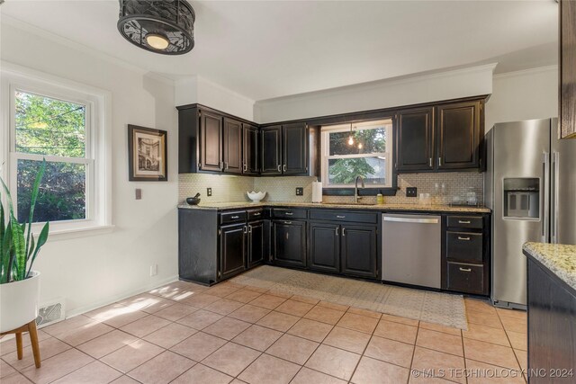3920 S Utica Ave, Tulsa, OK 74105 - kitchen featuring appliances with stainless steel finishes, a sink, light tile patterned floors, decorative backsplash, and crown molding