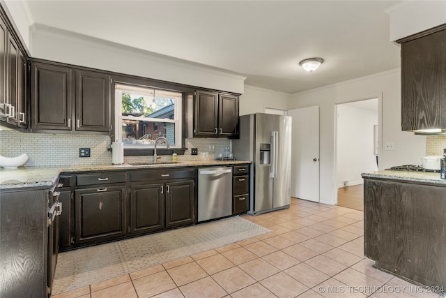 kitchen featuring sink, light stone counters, appliances with stainless steel finishes, crown molding, and decorative backsplash