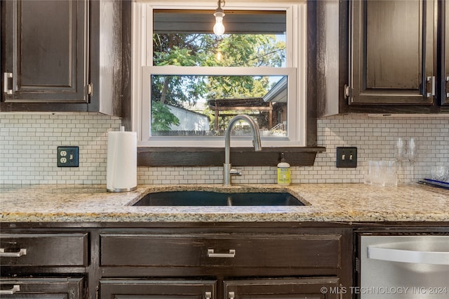 kitchen featuring dark brown cabinets, light stone countertops, decorative backsplash, sink, and stainless steel dishwasher