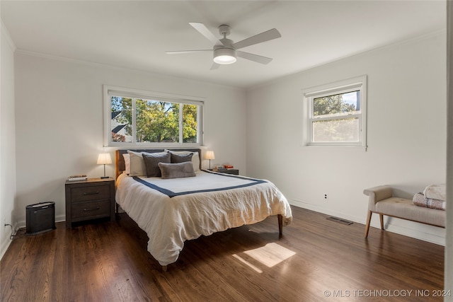 bedroom with dark wood-type flooring, ceiling fan, multiple windows, and ornamental molding