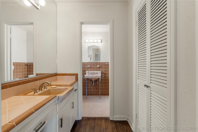 bathroom with tile walls, sink, hardwood / wood-style flooring, and ornamental molding