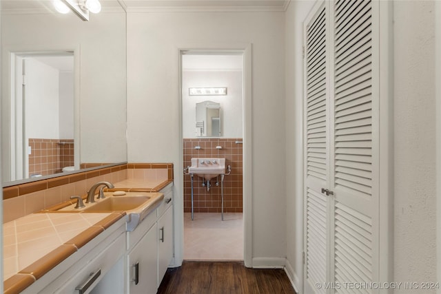3920 S Utica Ave, Tulsa, OK 74105 - bathroom featuring wood finished floors, tile walls, crown molding, and a sink