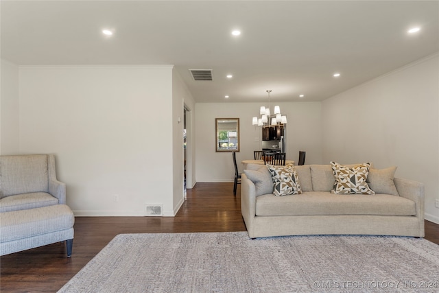 living room with ornamental molding, an inviting chandelier, and dark hardwood / wood-style floors