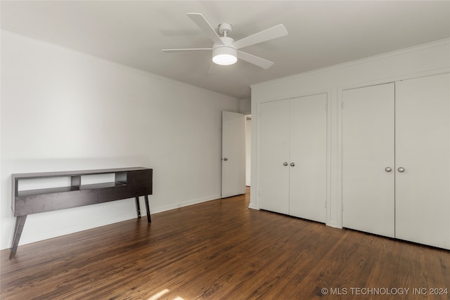 unfurnished bedroom featuring ceiling fan, multiple closets, dark hardwood / wood-style flooring, and ornamental molding