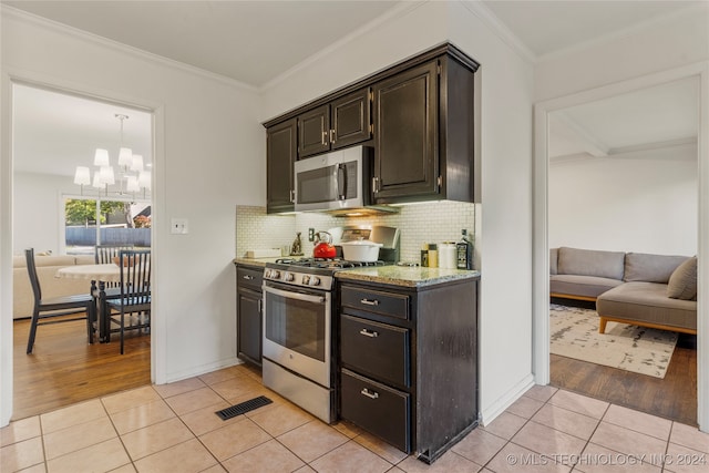 kitchen with stainless steel appliances, light hardwood / wood-style floors, a notable chandelier, tasteful backsplash, and crown molding