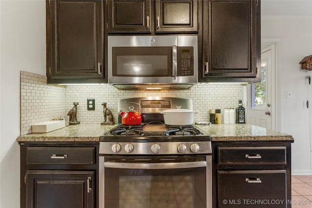 kitchen featuring decorative backsplash, light tile patterned floors, light stone countertops, dark brown cabinets, and appliances with stainless steel finishes