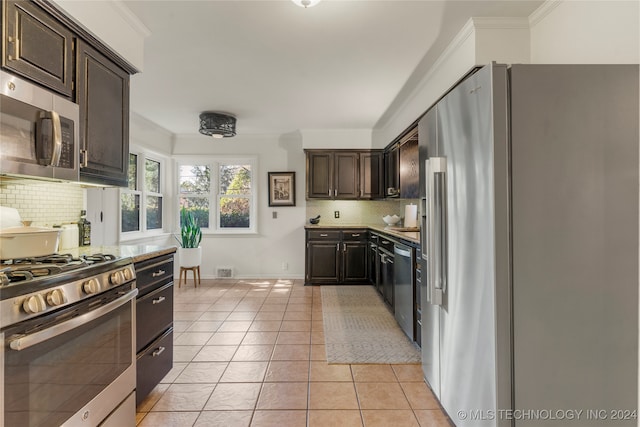 kitchen featuring dark brown cabinets, stainless steel appliances, light tile patterned flooring, and backsplash