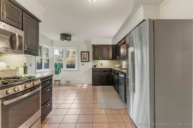 3920 S Utica Ave, Tulsa, OK 74105 - kitchen featuring appliances with stainless steel finishes, decorative backsplash, dark brown cabinets, light tile patterned floors, and light countertops