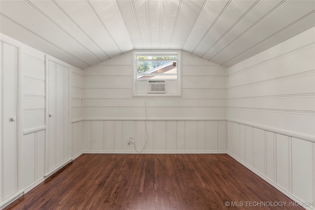 additional living space with wooden walls, dark wood-type flooring, cooling unit, and vaulted ceiling