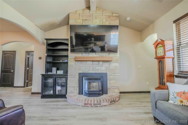 living room featuring light hardwood / wood-style floors, a wood stove, built in shelves, and lofted ceiling with beams