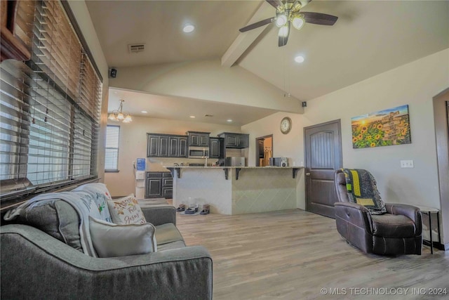 living room with vaulted ceiling with beams, ceiling fan with notable chandelier, and light hardwood / wood-style flooring