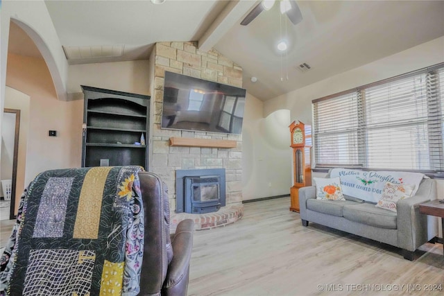 living room with light wood-type flooring, ceiling fan, a wood stove, and lofted ceiling with beams