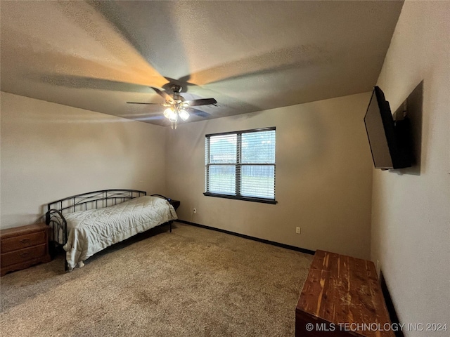 carpeted bedroom featuring ceiling fan and a textured ceiling