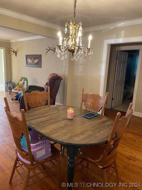 dining room with hardwood / wood-style flooring, a notable chandelier, and ornamental molding