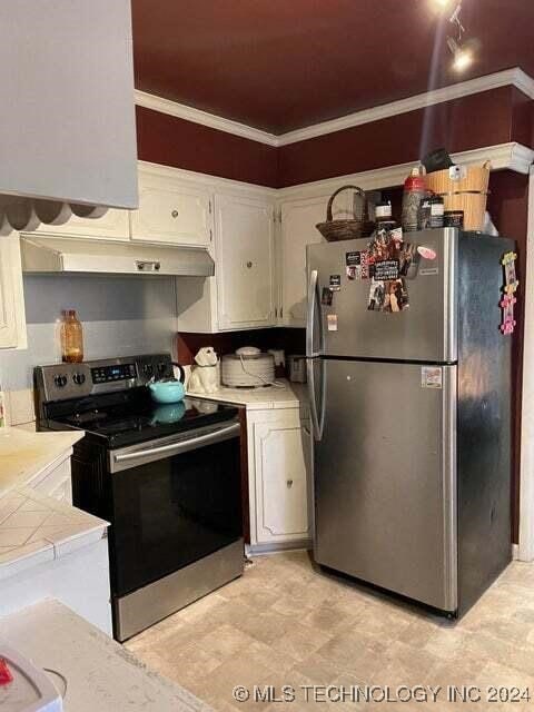 kitchen with white cabinets, stainless steel appliances, tile countertops, and crown molding