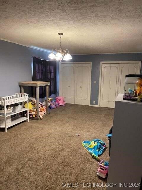 rec room with a textured ceiling, a notable chandelier, and carpet floors