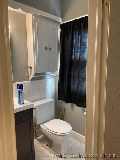 bathroom with vanity, tile patterned floors, toilet, and tasteful backsplash