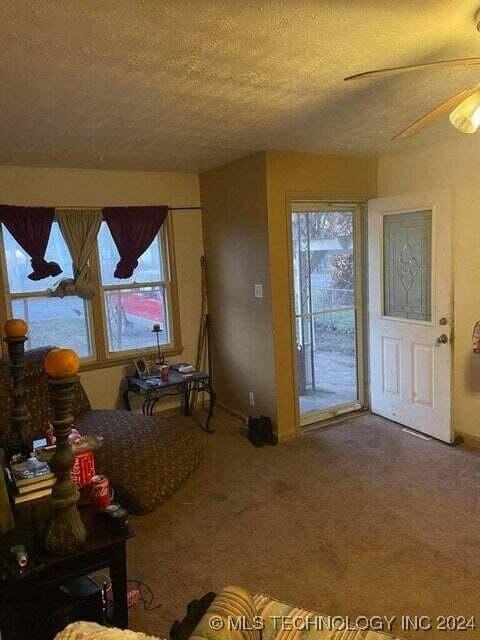 carpeted living room with a textured ceiling and ceiling fan