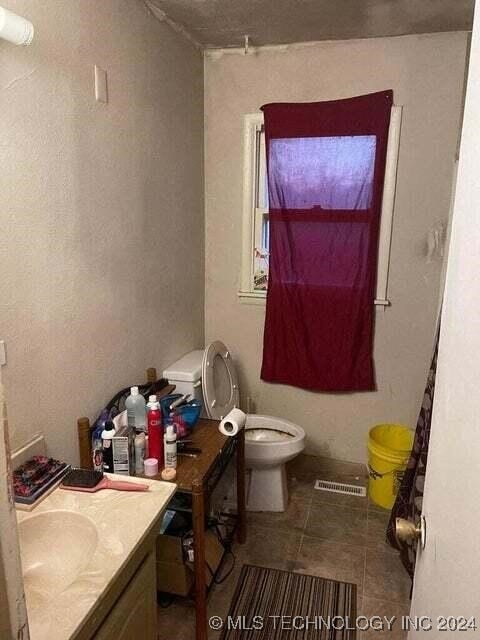 bathroom with toilet, vanity, and tile patterned floors