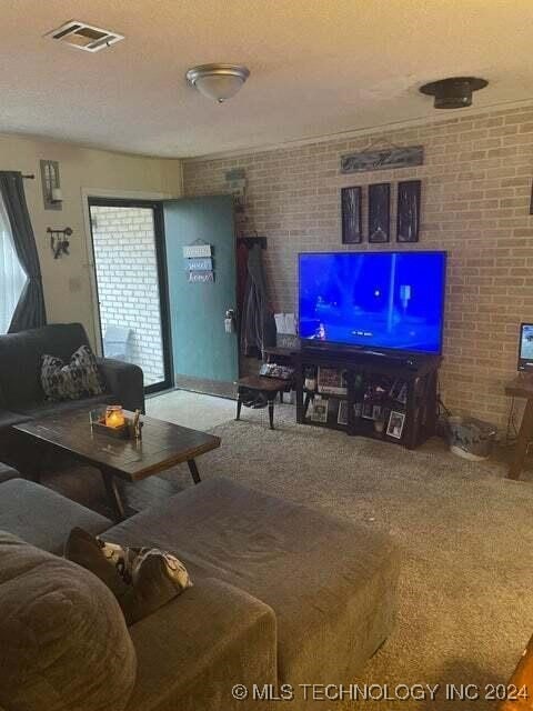 living room featuring carpet flooring, a wealth of natural light, brick wall, and a textured ceiling