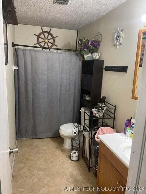 bathroom featuring walk in shower, vanity, a textured ceiling, and toilet