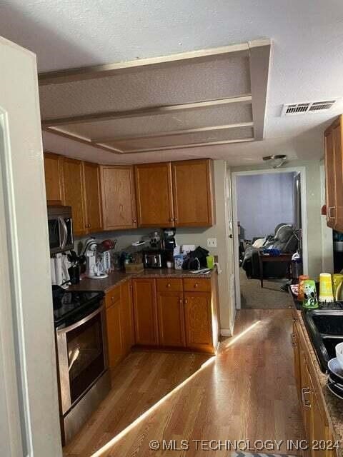 kitchen with a textured ceiling, black / electric stove, and hardwood / wood-style flooring