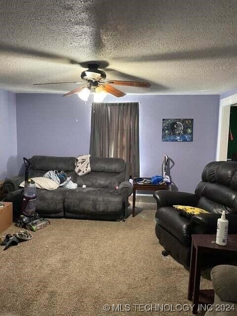 carpeted living room featuring a textured ceiling and ceiling fan