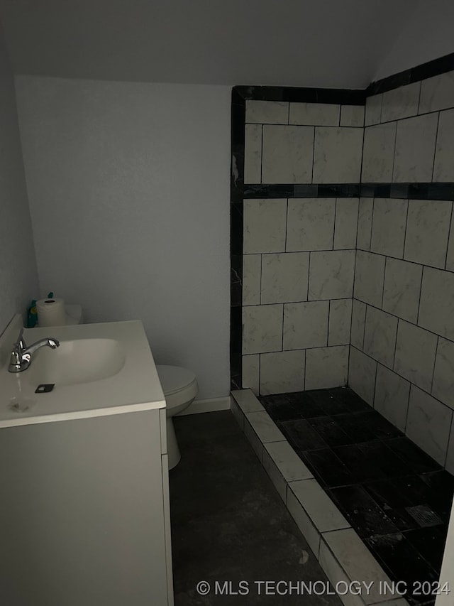 bathroom featuring tiled shower, vanity, and toilet