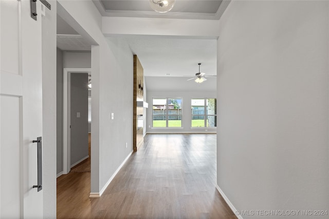 hall with wood-type flooring and a barn door