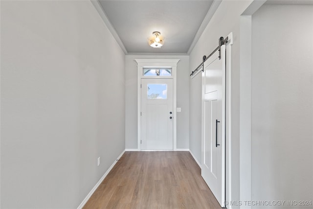 doorway featuring ornamental molding, light hardwood / wood-style floors, and a barn door