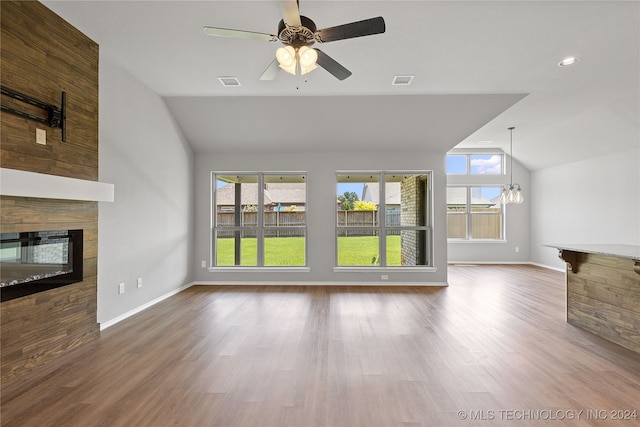 unfurnished living room with vaulted ceiling, ceiling fan with notable chandelier, wood-type flooring, and a tile fireplace