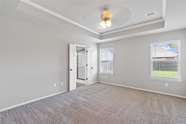 carpeted spare room featuring ceiling fan, a raised ceiling, and crown molding