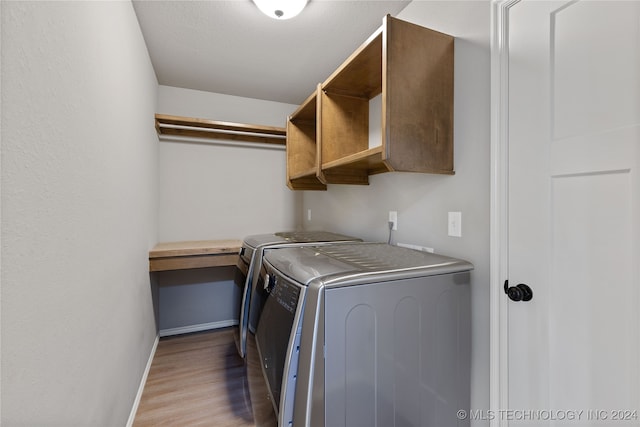 laundry area featuring a textured ceiling, washing machine and dryer, and light hardwood / wood-style flooring