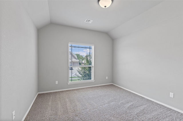 carpeted empty room featuring vaulted ceiling