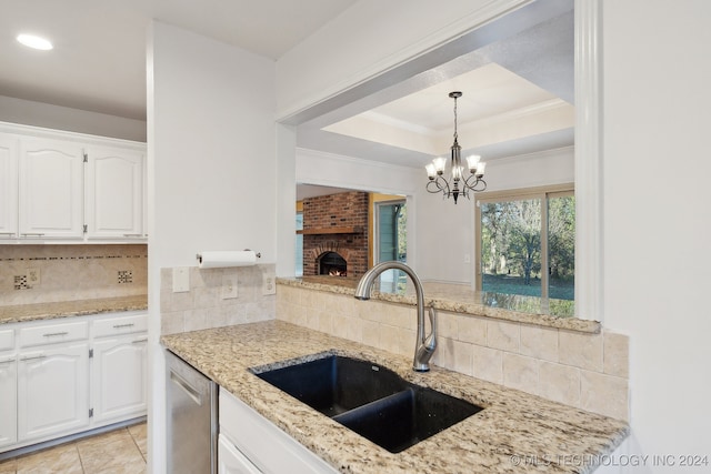 kitchen with decorative backsplash, white cabinetry, a brick fireplace, and sink