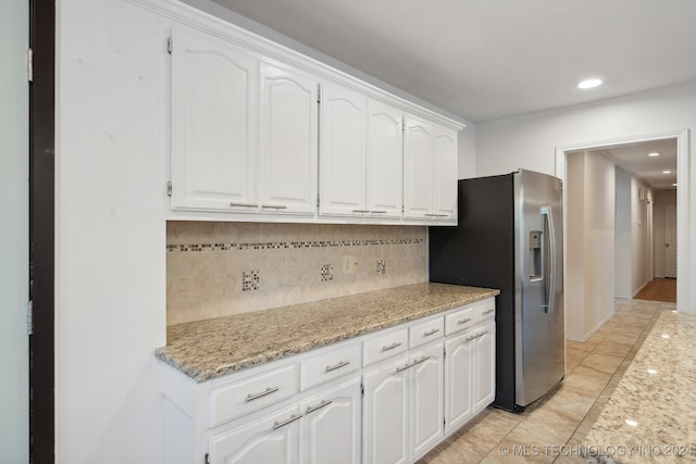 kitchen with stainless steel refrigerator with ice dispenser, tasteful backsplash, white cabinetry, and light stone counters