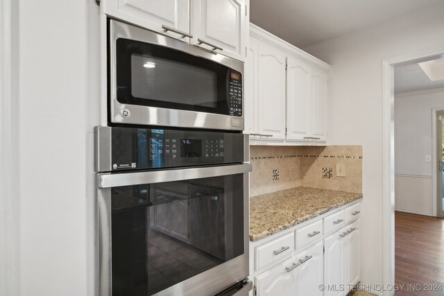 kitchen featuring backsplash, dark wood-type flooring, light stone countertops, white cabinetry, and stainless steel appliances