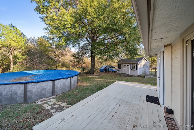 wooden terrace with a lawn, a storage shed, and a covered pool