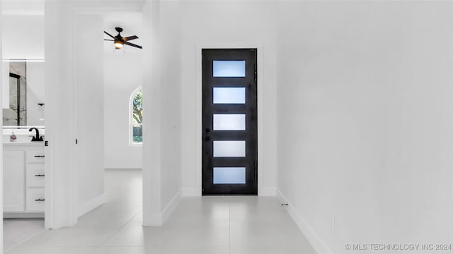 entrance foyer with ceiling fan, light tile patterned floors, sink, and a high ceiling