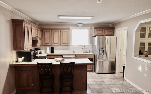 kitchen with a peninsula, a sink, stainless steel appliances, light countertops, and crown molding