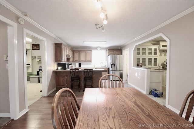 dining room with wood finished floors, baseboards, and ornamental molding