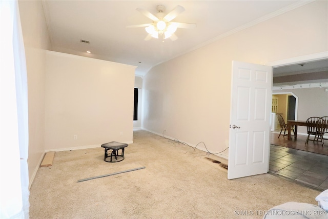 carpeted spare room featuring a ceiling fan, visible vents, baseboards, arched walkways, and crown molding