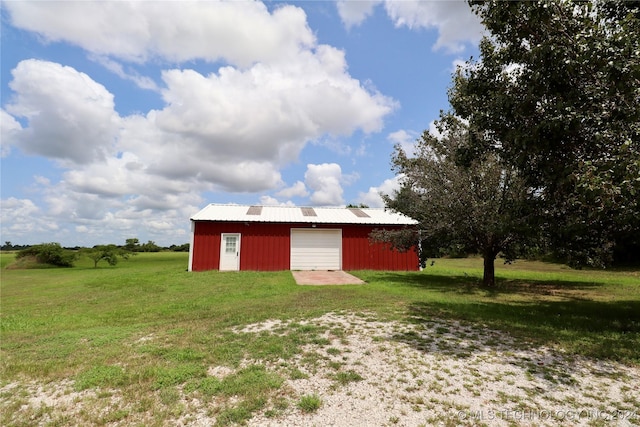 view of pole building with a garage, a lawn, and driveway