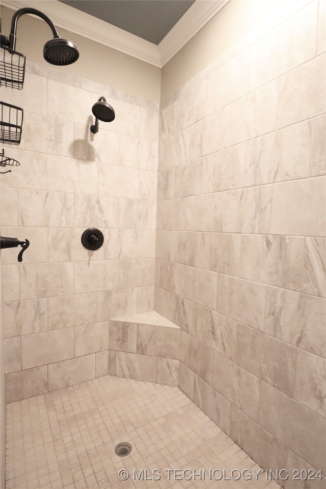 bathroom with a tile shower and ornamental molding