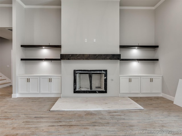 interior space featuring white cabinets, ornamental molding, and light hardwood / wood-style floors