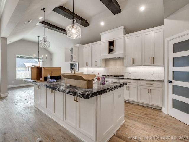 kitchen featuring white cabinets, light wood-type flooring, vaulted ceiling with beams, and pendant lighting