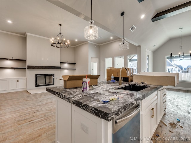 kitchen with decorative light fixtures, dark stone countertops, a spacious island, sink, and white cabinets