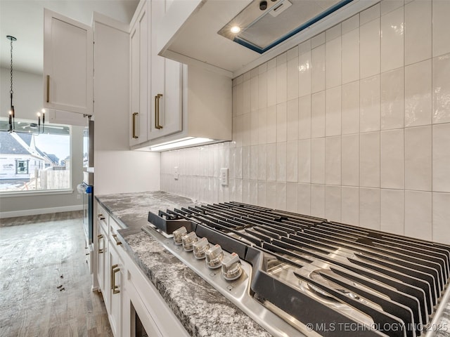 room details with white cabinets, backsplash, appliances with stainless steel finishes, and light stone counters