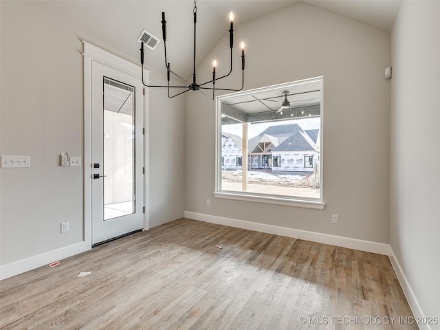 unfurnished dining area with vaulted ceiling, a chandelier, and light hardwood / wood-style flooring